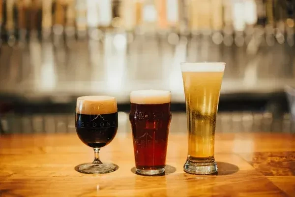 Three distinct beers, from dark stout to golden lager, on a bar.