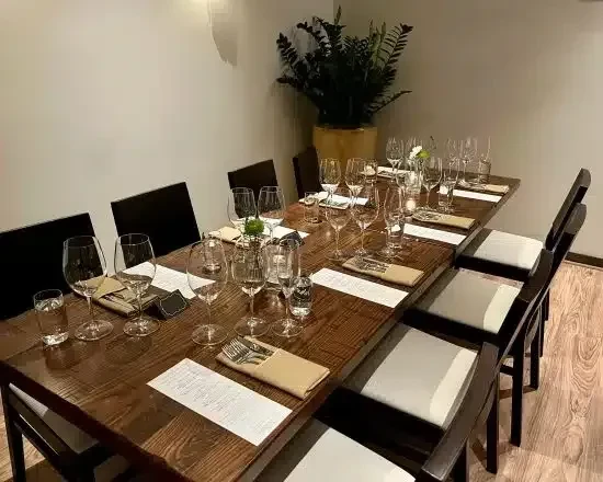 Long wooden dining table meticulously set for twelve, with a plant centerpiece.