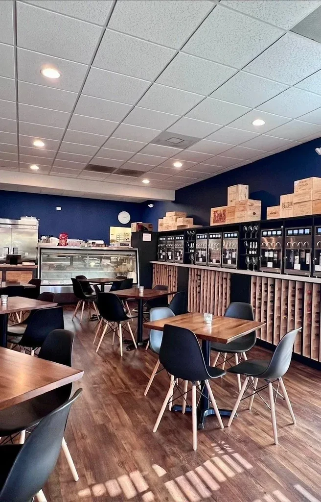 Modern wine bar with Eames-style chairs, wine dispensers, and wood flooring.