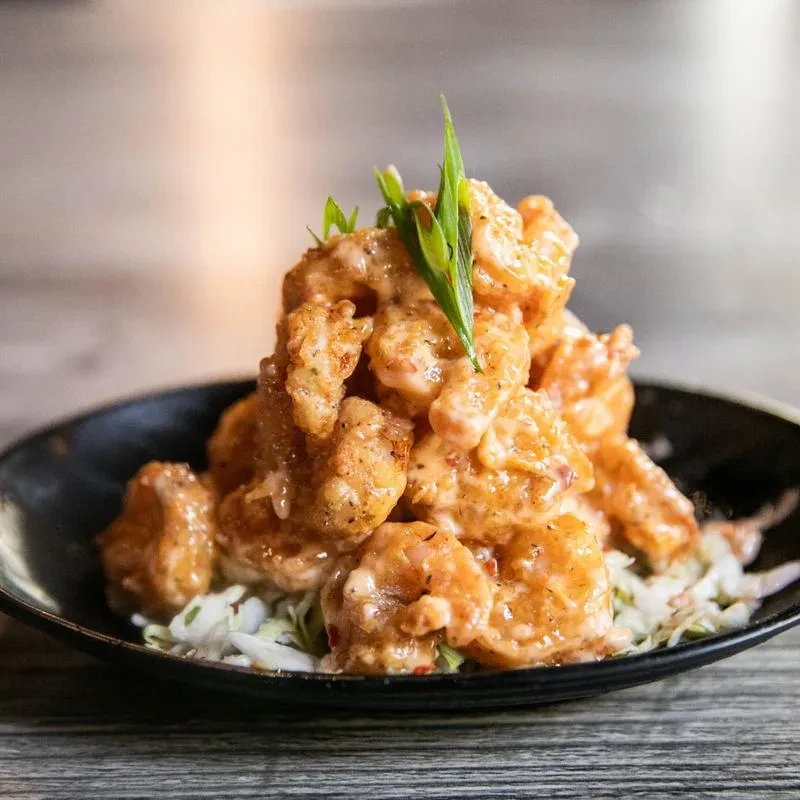 Deep-fried shrimp in creamy orange sauce over shredded greens, with chives.
