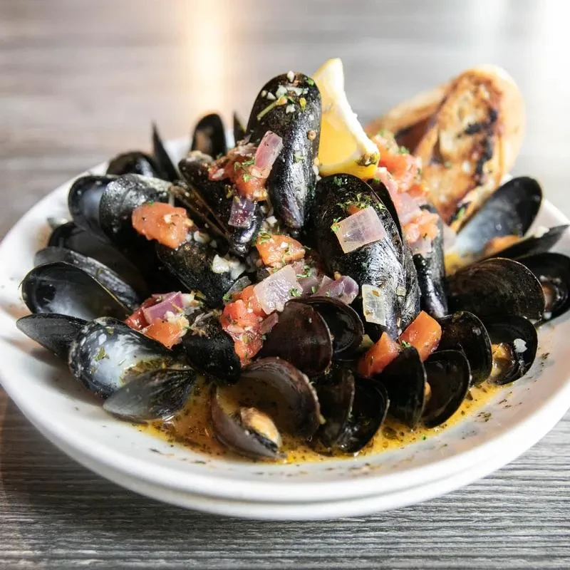 Black mussels with tomato-onion relish, lemon, and toasted bread.