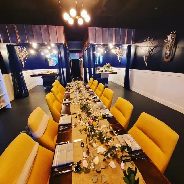 Decorated private dining room with long wooden table and yellow chairs.