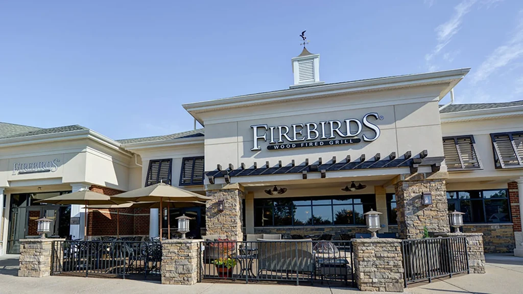 FIREBIRDS WOOD FIRED GRILL exterior with sunny patio and bird weathervane.