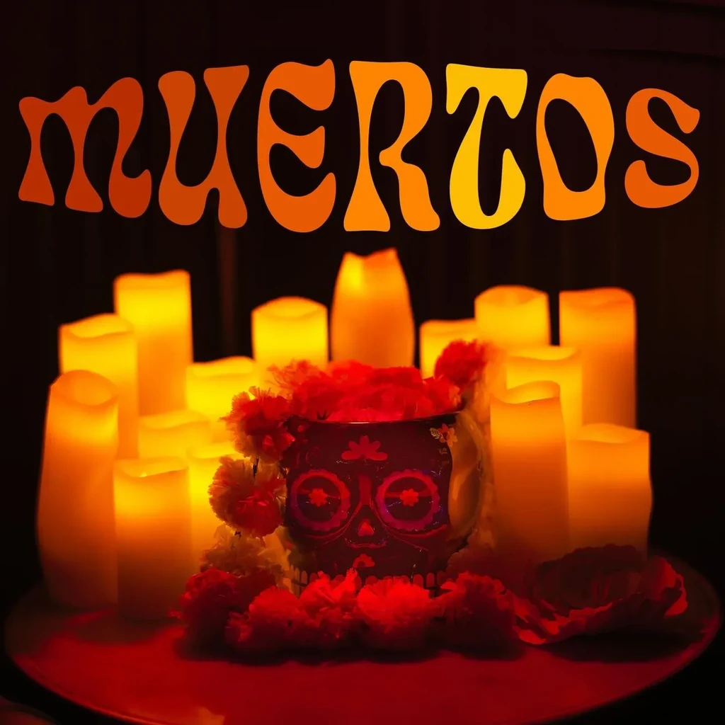 Festive Día de los Muertos display: candles, sugar skull, flowers, 'MUERTOS' sign.