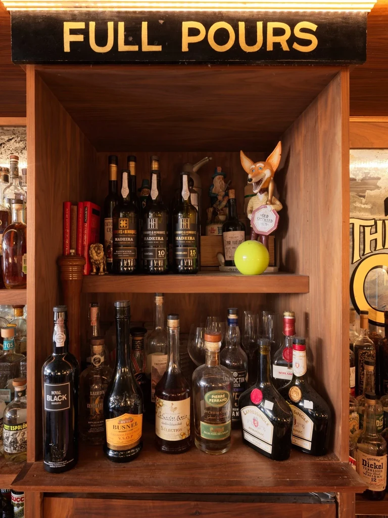 Well-stocked wooden bar cabinet with diverse liquor bottles and 'FULL POURS' sign.