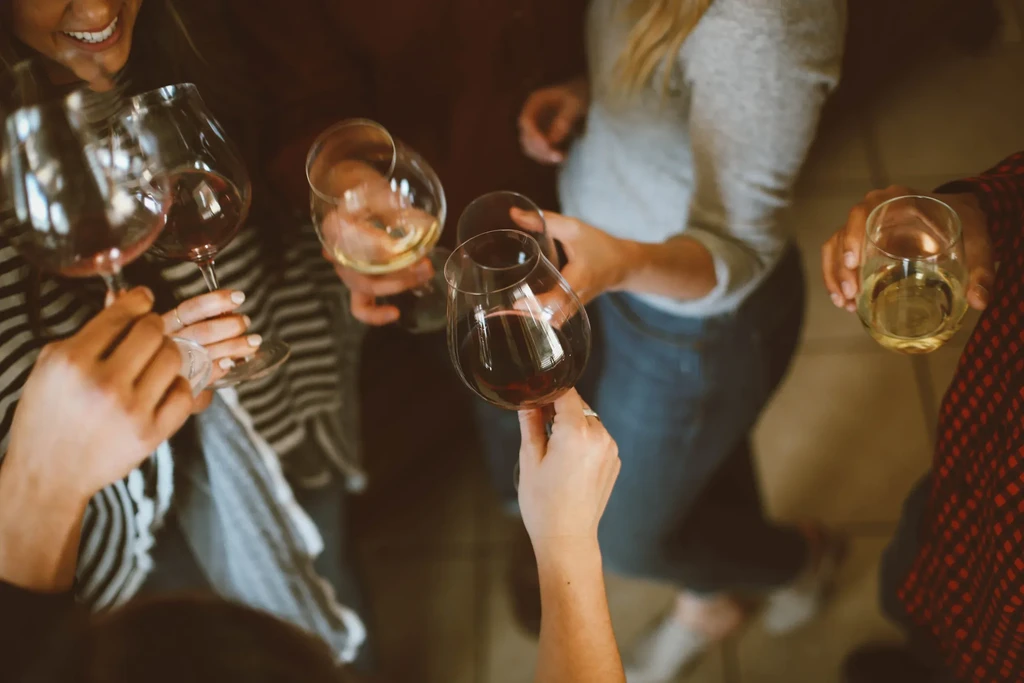 Hands clinking red and white wine glasses during a toast.
