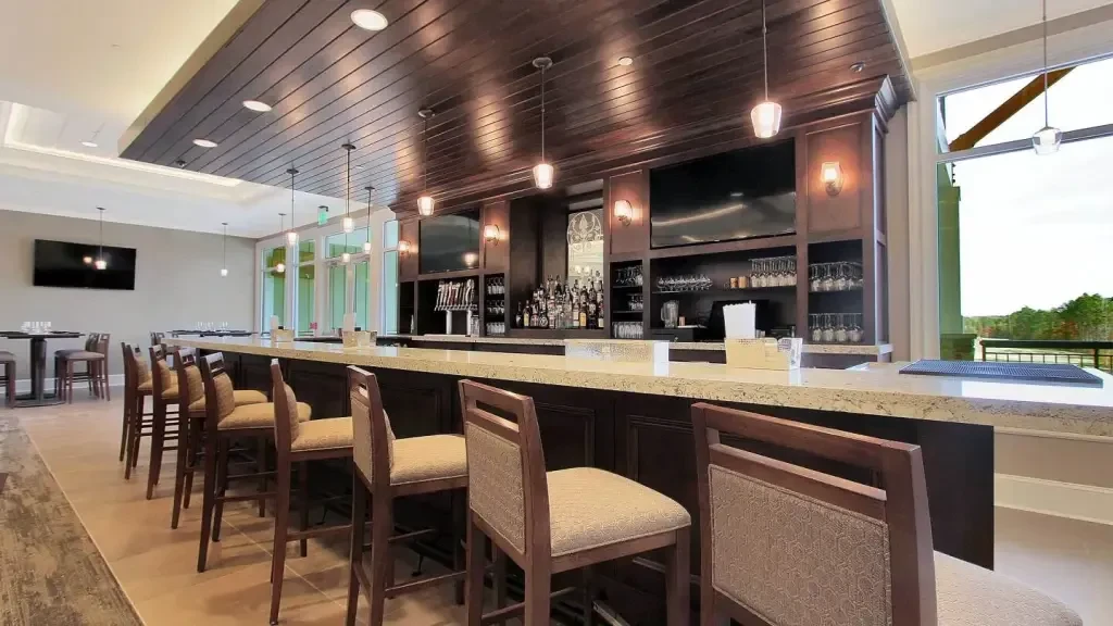 Modern upscale bar with dark wood, liquor bottles, and mounted TVs.