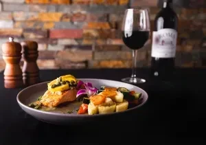 Pan-seared salmon with lemon, capers, vegetables, and red wine.