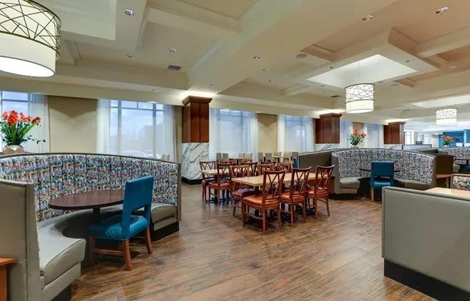 Spacious, modern restaurant interior with mosaic booths, wooden tables, and bright natural light.