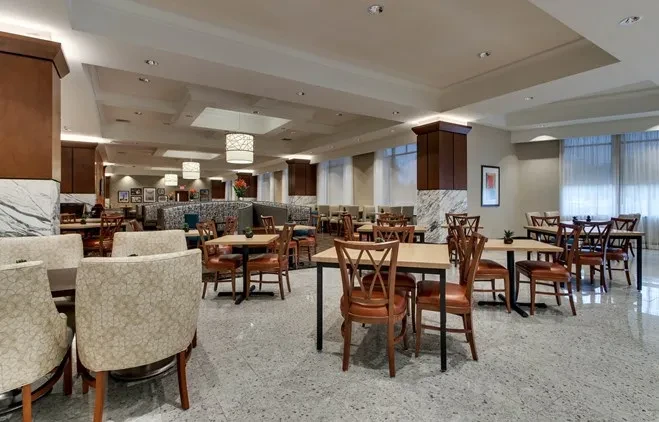 Spacious, modern restaurant interior with varied seating, high ceilings, and windows.