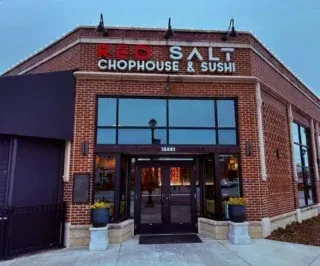 Red brick RED SALT CHOPHOUSE & SUSHI building, illuminated sign, at dusk.