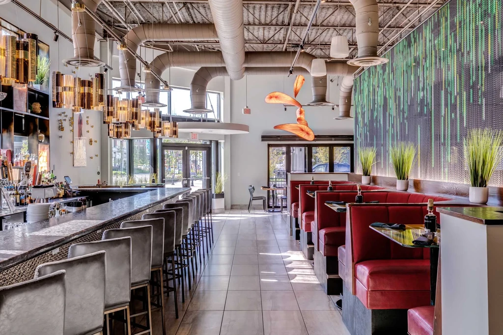 Modern restaurant interior: long bar, red booths, green digital rain art.