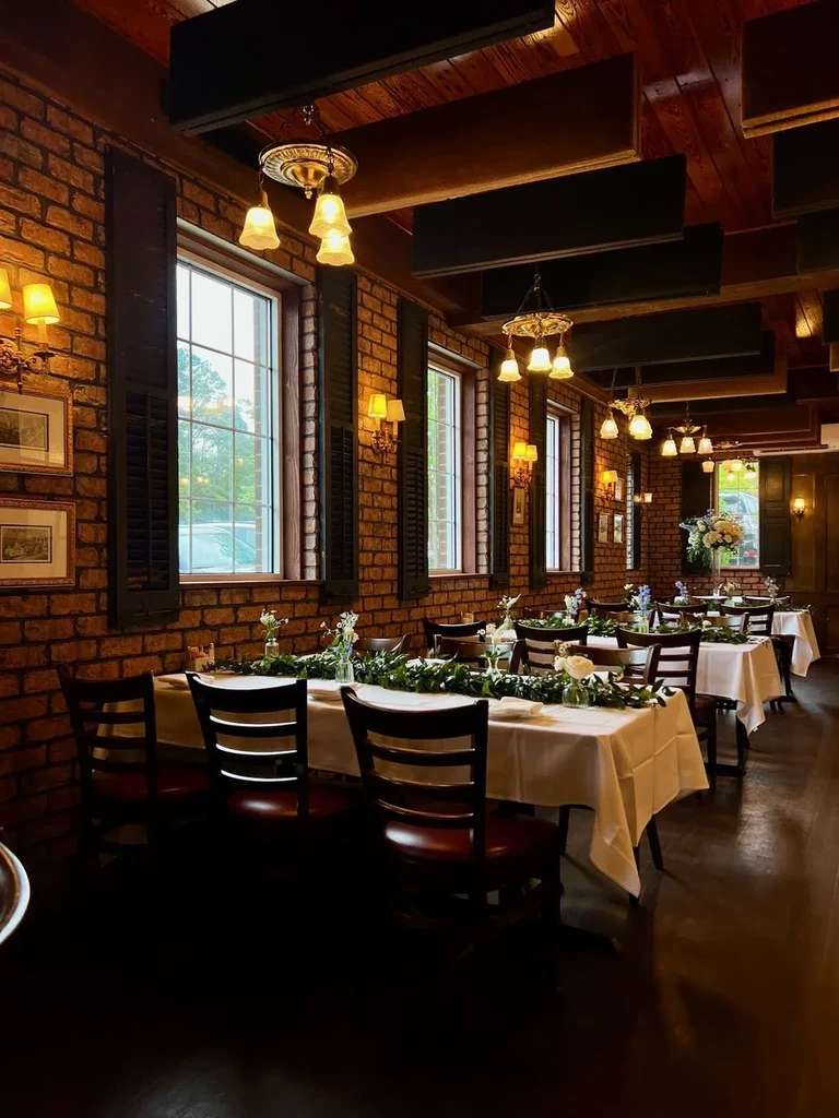 Rustic restaurant dining room with elegant tables, brick walls, and chandeliers.