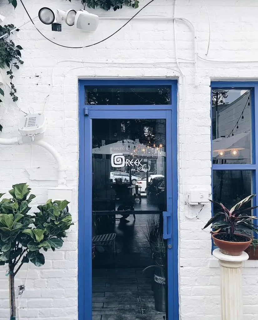 White brick restaurant with blue door and 'GREEK on Cary' logo.