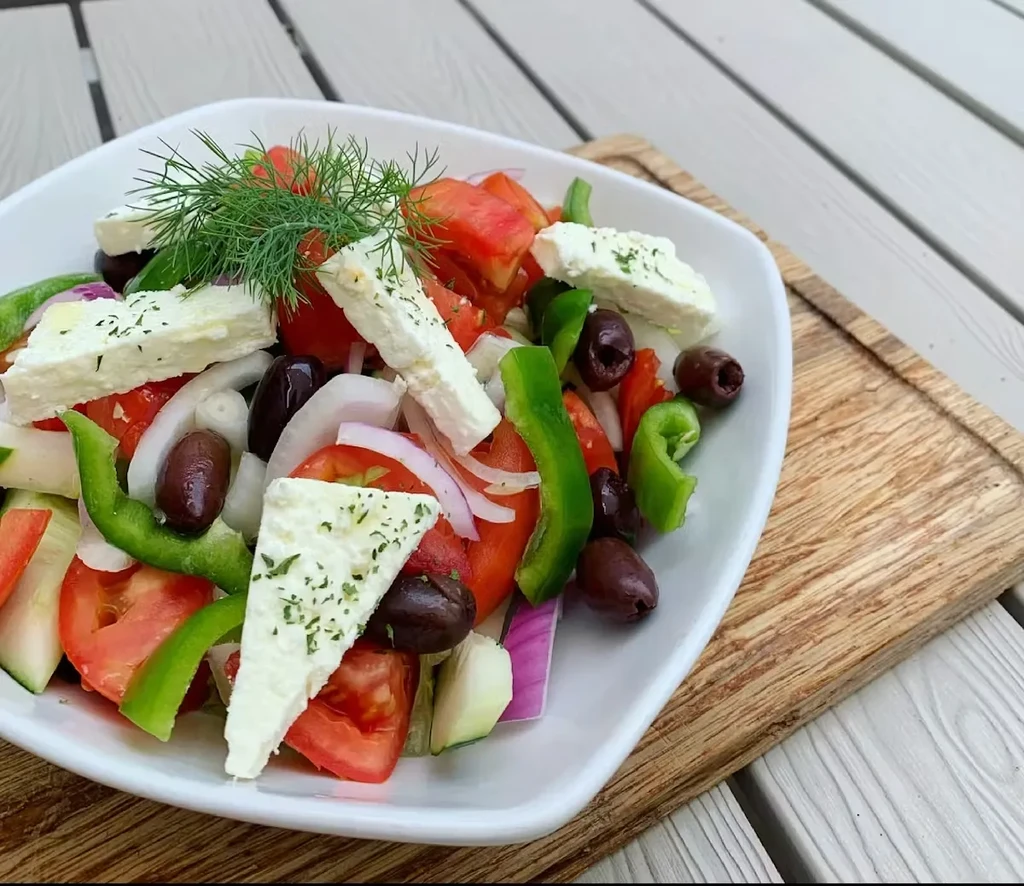 Fresh Greek salad with tomatoes, peppers, feta, olives, and dill.