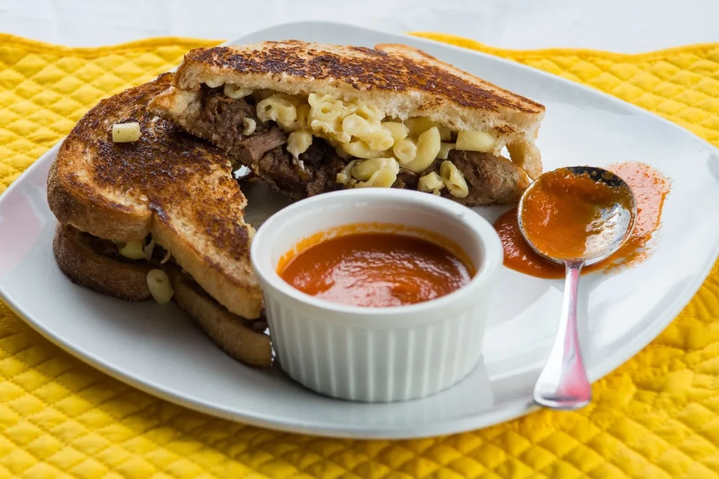 Close-up of grilled sandwich with dark meat and macaroni and cheese.