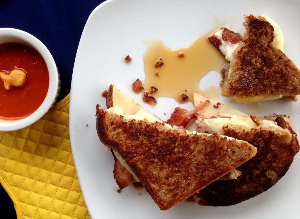 Grilled sandwich with bacon, apple, cheese, syrup, and tomato soup.
