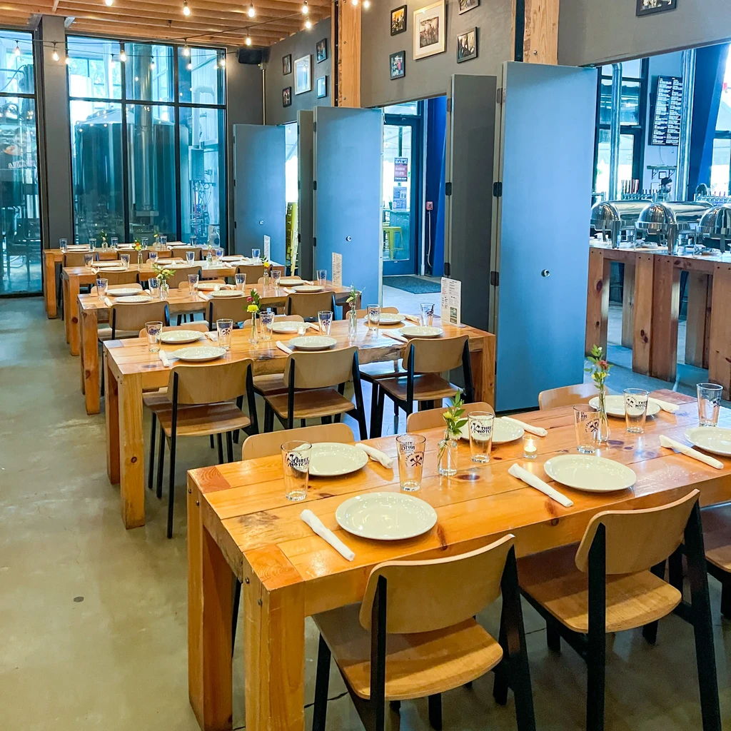 Empty industrial-chic brewpub dining area with set tables and buffet.