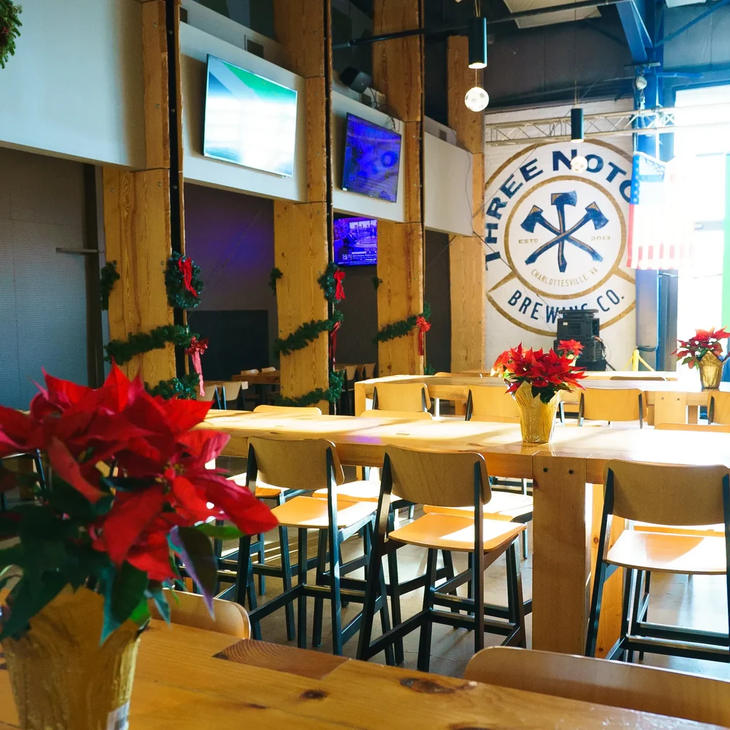 Festive brewery interior with communal tables and Three Notch'd Brewing logo.