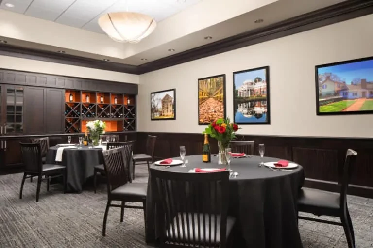 Elegant restaurant dining room with set tables, wine rack, and chandelier.