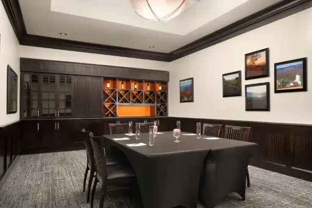 Private dining room with a set table, wine rack, and paintings.