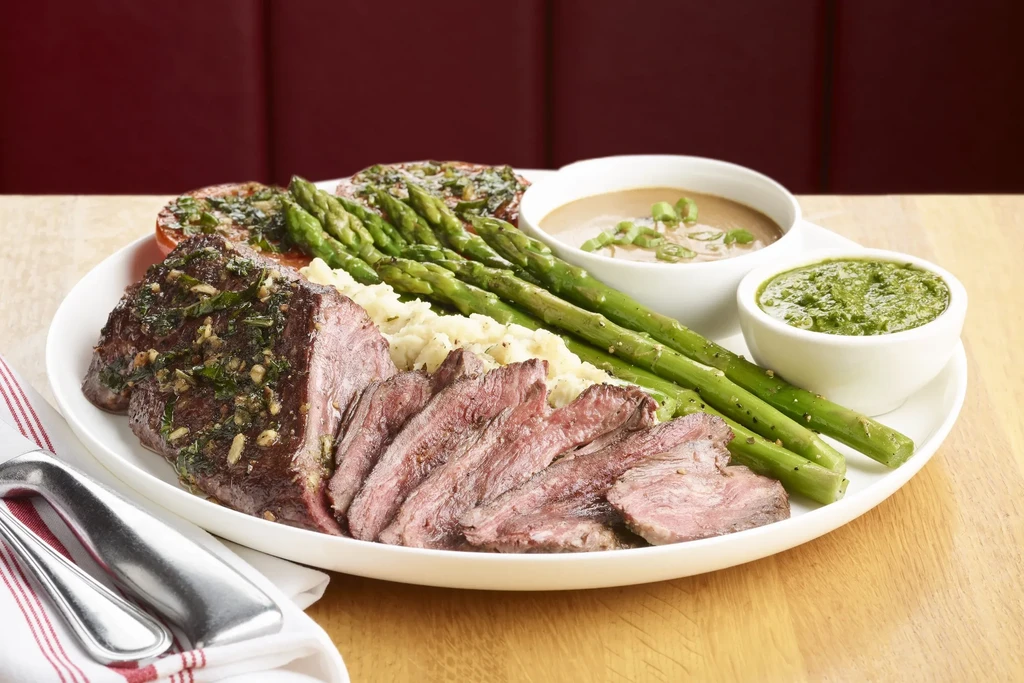 A restaurant meal: grilled steak, mashed potatoes, asparagus, and sauces.