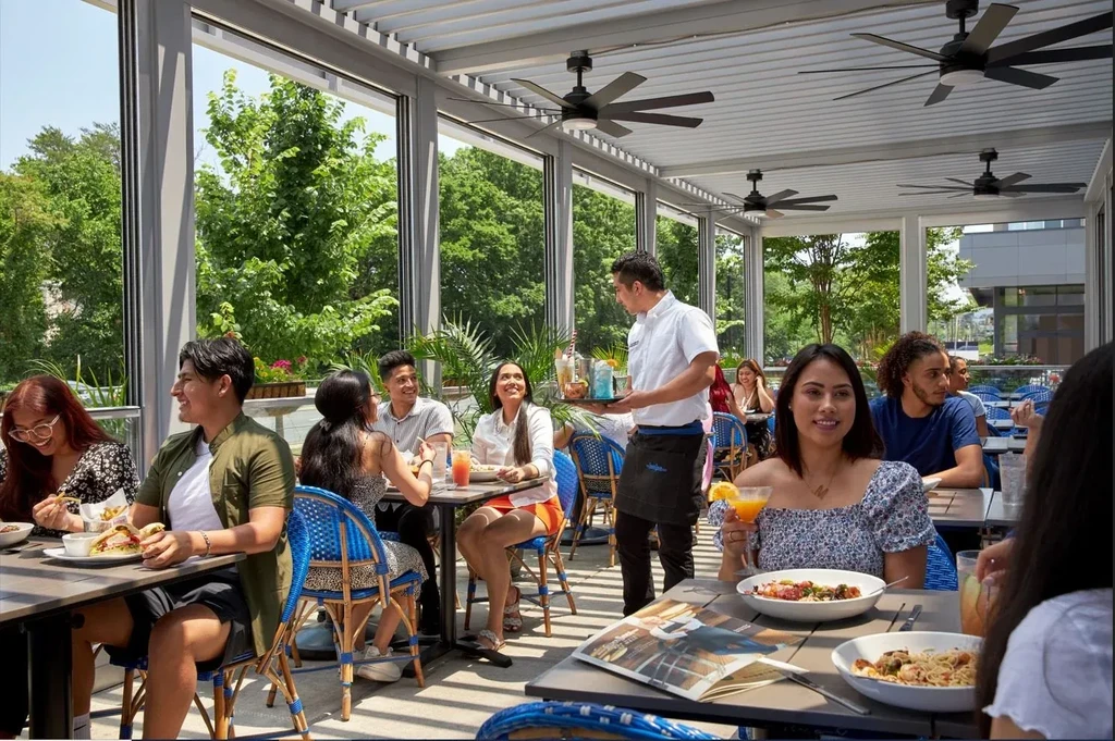 Busy restaurant patio with waiter serving colorful drinks to patrons.