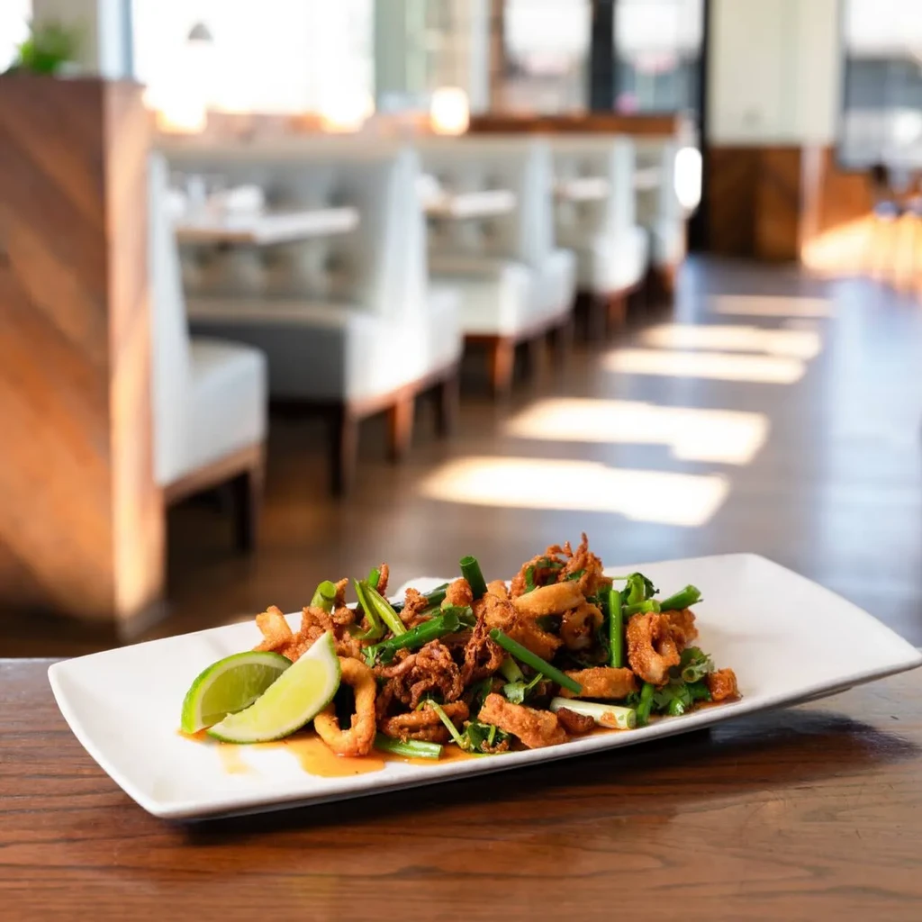 Fried calamari appetizer on a white plate in a bright restaurant.