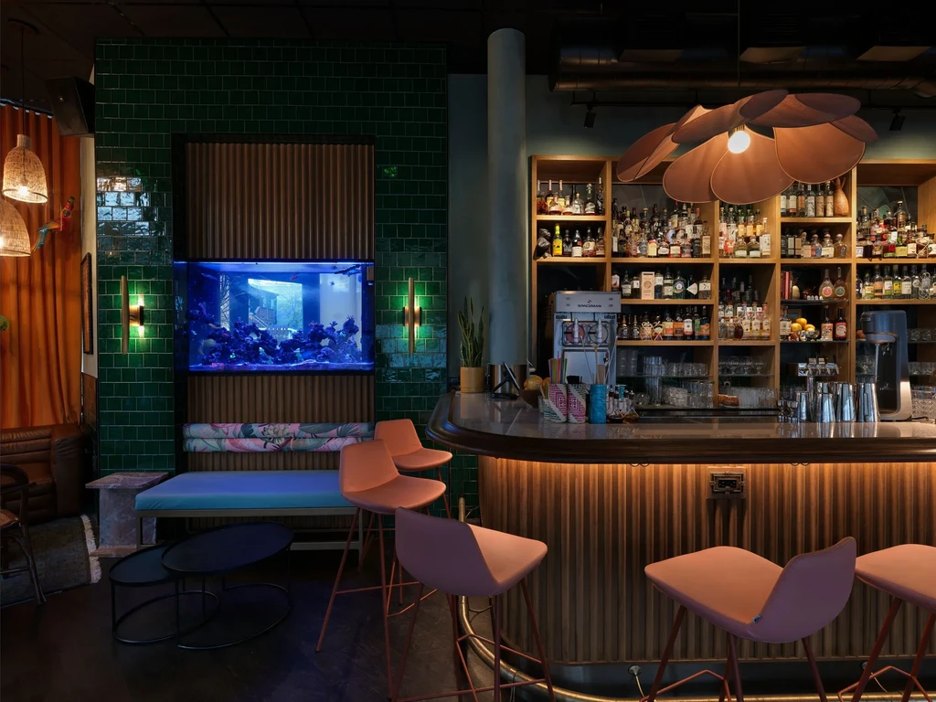 Modern bar interior with stocked liquor bottles and glowing aquarium.
