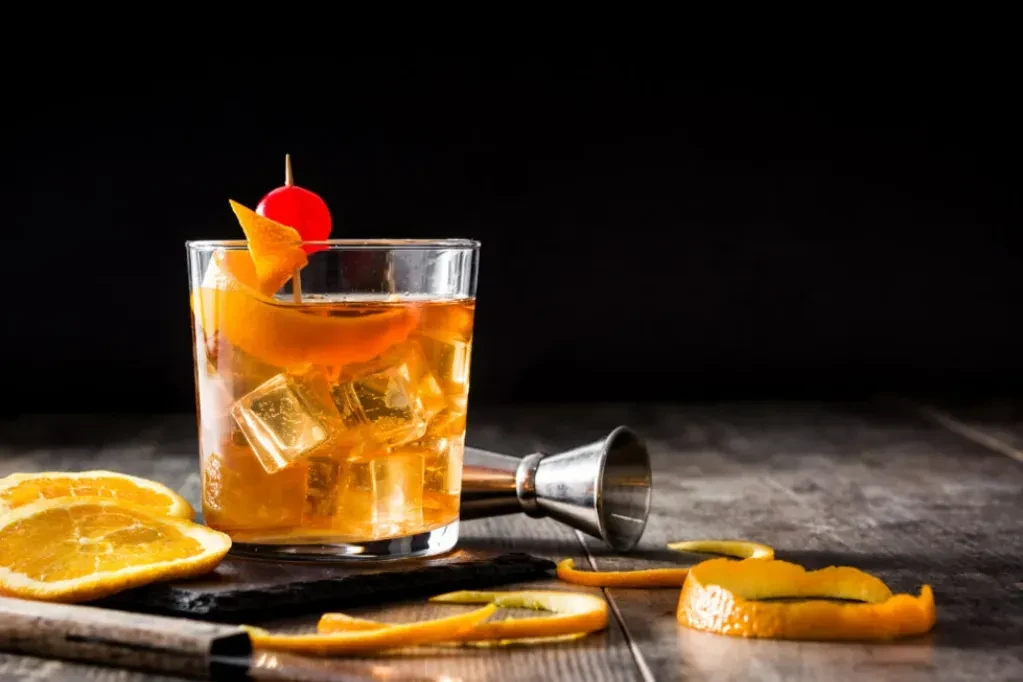 Still life of an Old Fashioned cocktail with oranges and jigger.