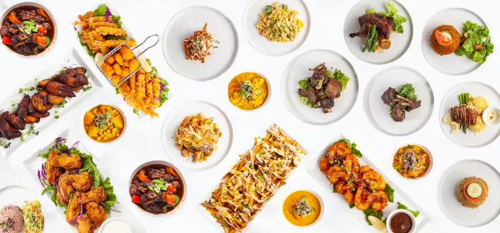 Overhead shot: many diverse, vibrantly plated dishes on a white background.