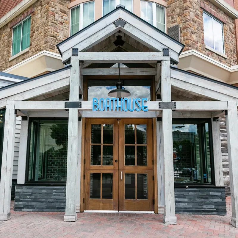Stone Boathouse entrance with illuminated sign and rustic wooden doors.