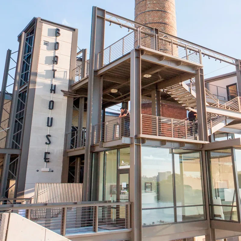 BOATHOUSE: Industrial-modern building with glass, steel, balconies, brick chimney.