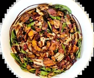 Overhead view of a hearty salad with greens, bacon, chicken, dark dressing.