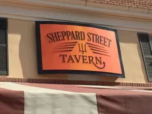 Close-up of Sheppard Street Tavern sign with orange gradient and trident.