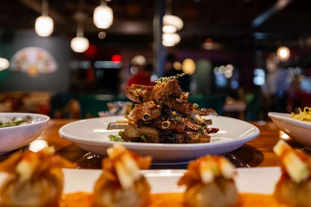 Plate of glistening barbecue ribs with green onions in restaurant.