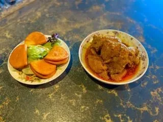 Golden buns with salad and a bowl of brown meat stew.