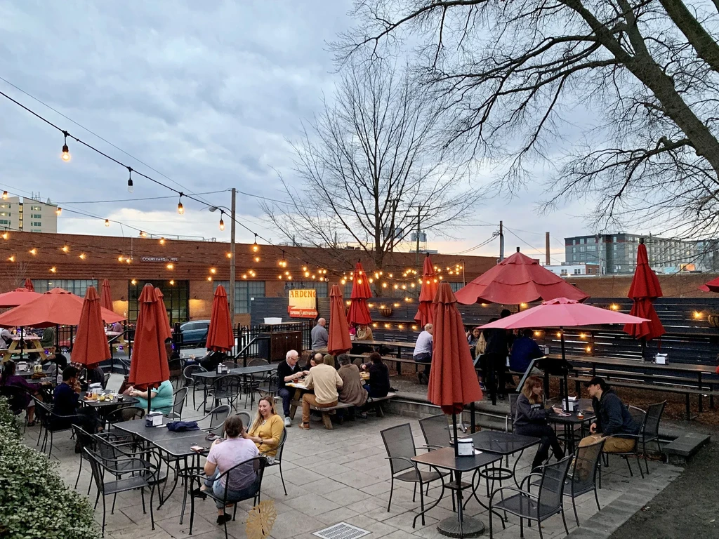 Outdoor restaurant patio filled with people, string lights, and red umbrellas.