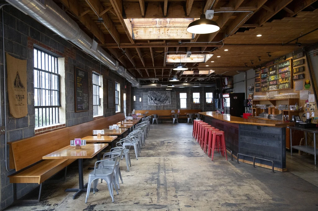 Empty industrial-chic restaurant with bar, exposed brick, and wood beams.