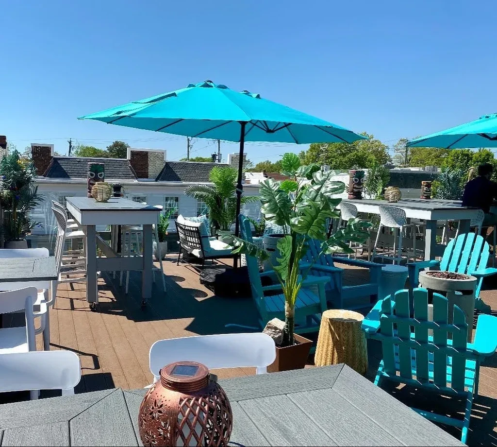 Sunny, tiki-themed rooftop patio with turquoise umbrellas and varied seating.
