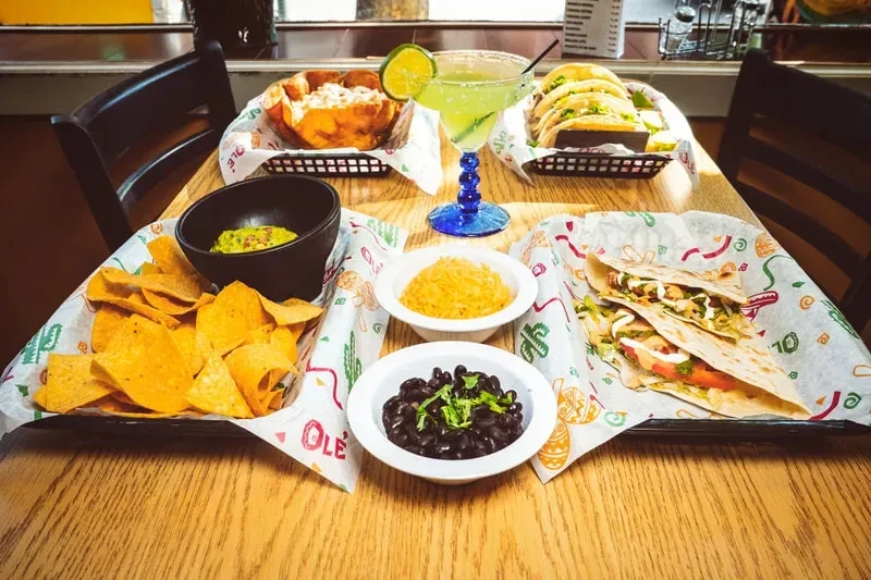 Mexican dishes: tacos, chips, guacamole, rice, beans, and a margarita.