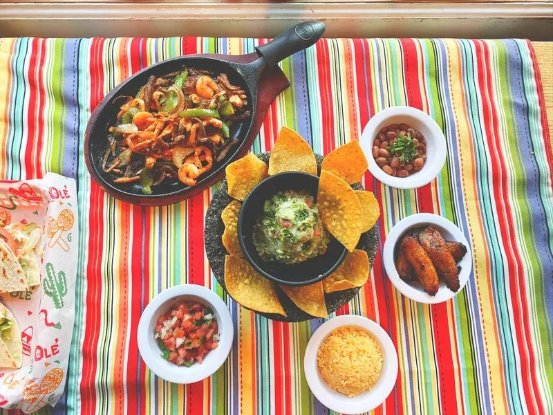 Sizzling fajitas in skillet, guacamole, chips, and Mexican sides.
