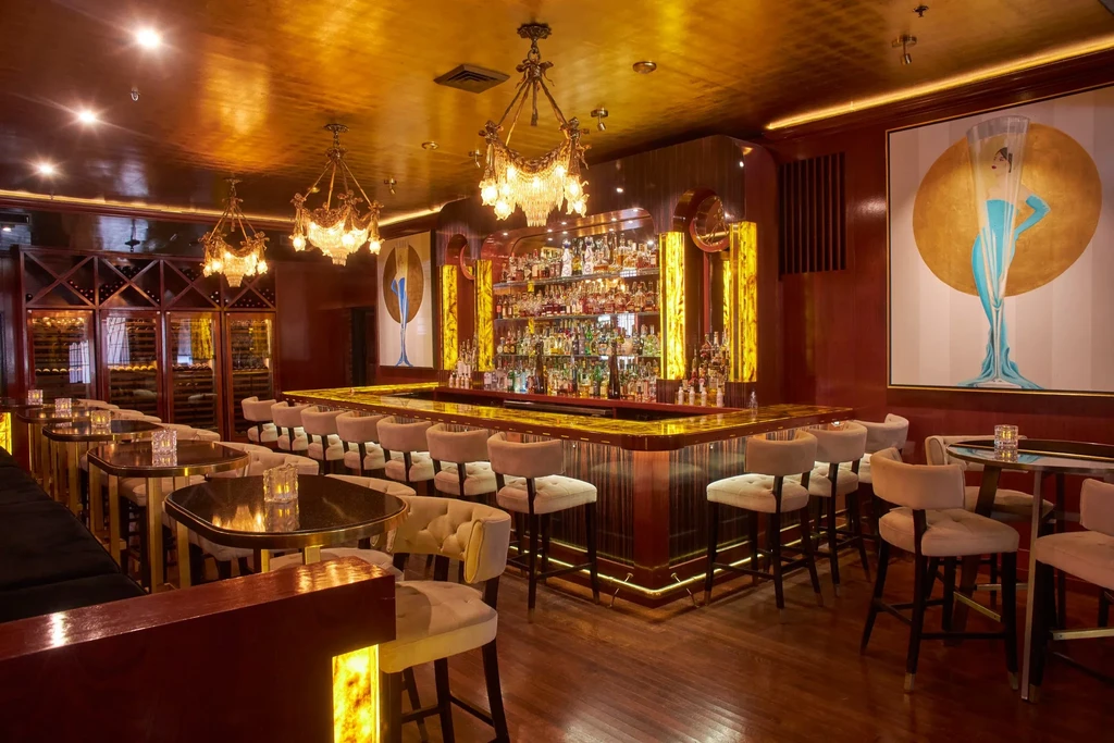 Luxurious, well-stocked U-shaped bar with red walls and Art Deco art.