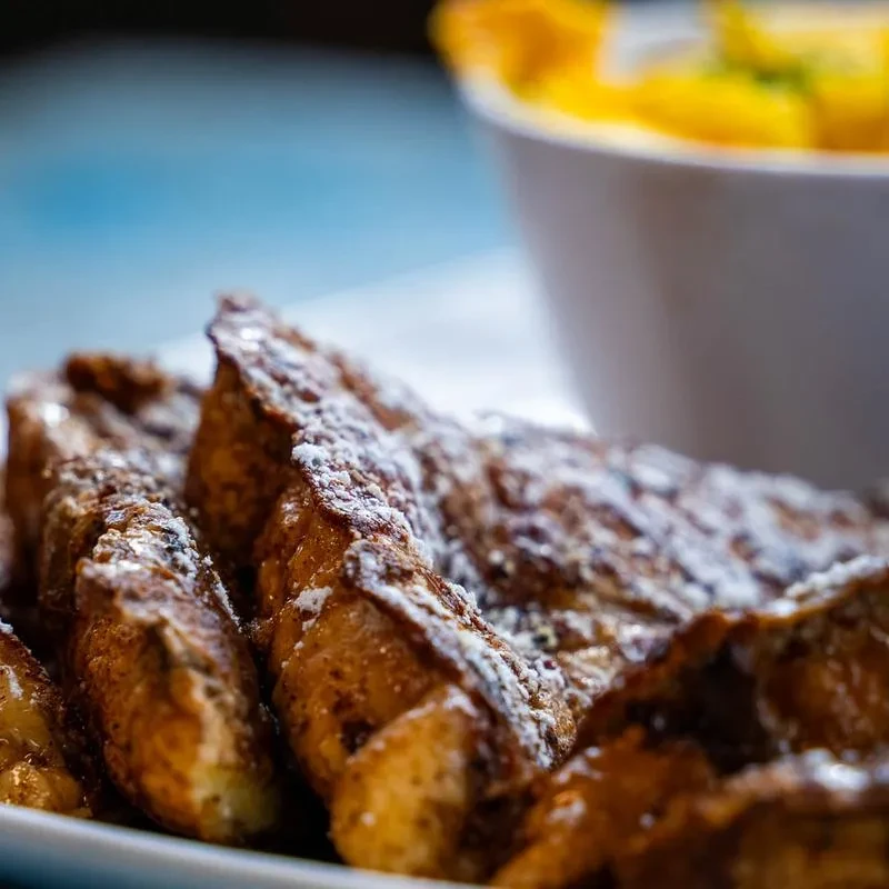 Crispy golden French toast sticks or churros dusted with powdered sugar.