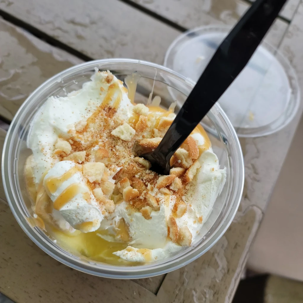Close-up of layered banana pudding with whipped cream, caramel, crumbles.
