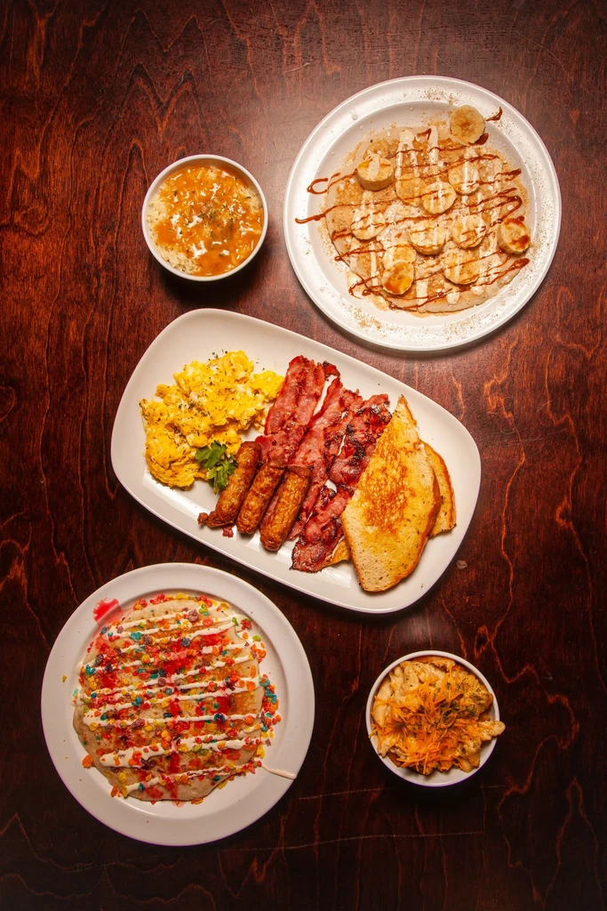 Assorted breakfast and brunch foods including eggs, bacon, pancakes, and grits.