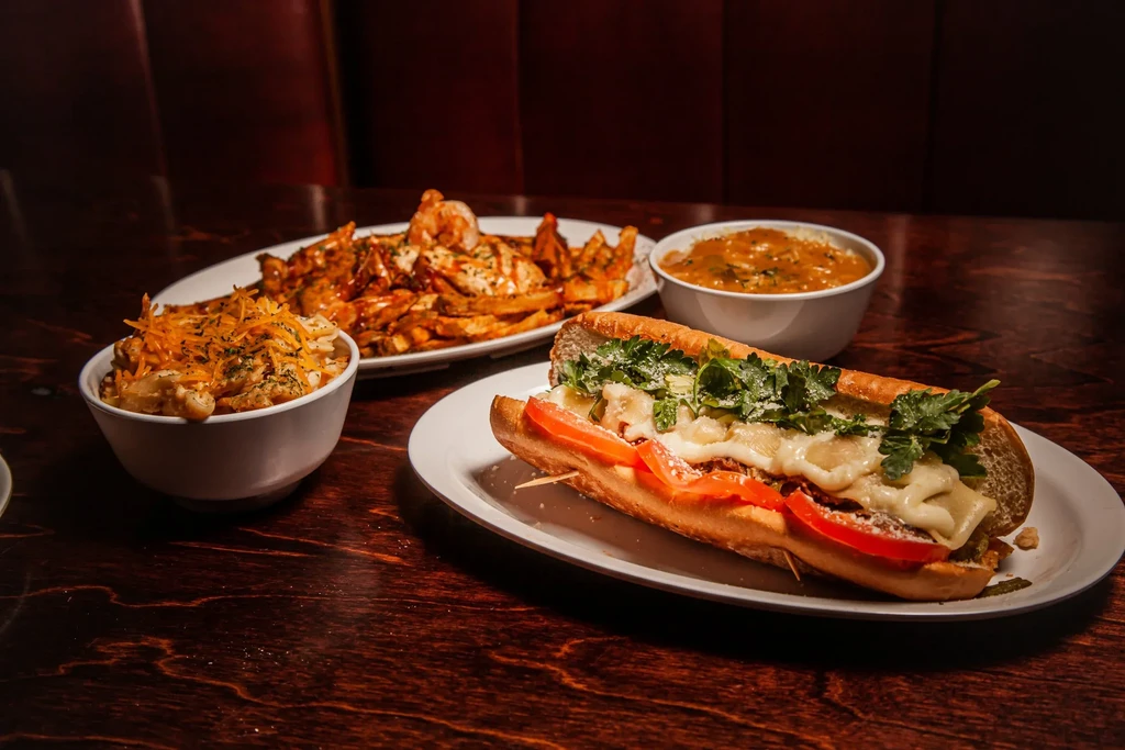 Restaurant table with sub, mac and cheese, shrimp fries, and stew.