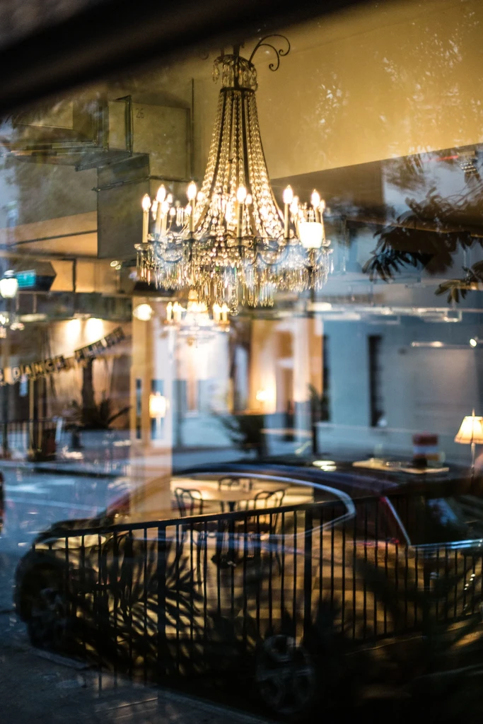 Ornate crystal chandelier seen through a reflective window with layered scenes.