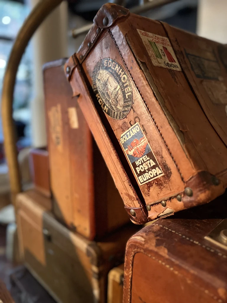 Close-up of stacked vintage brown leather suitcases with travel stickers.