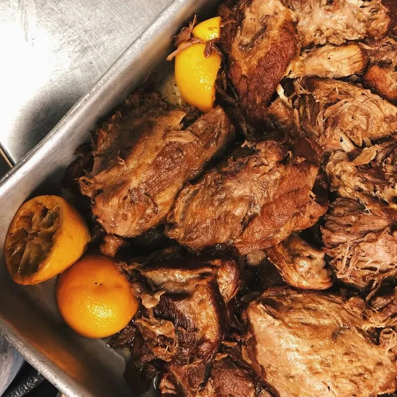 Roasted shredded meat with citrus in a metal pan.